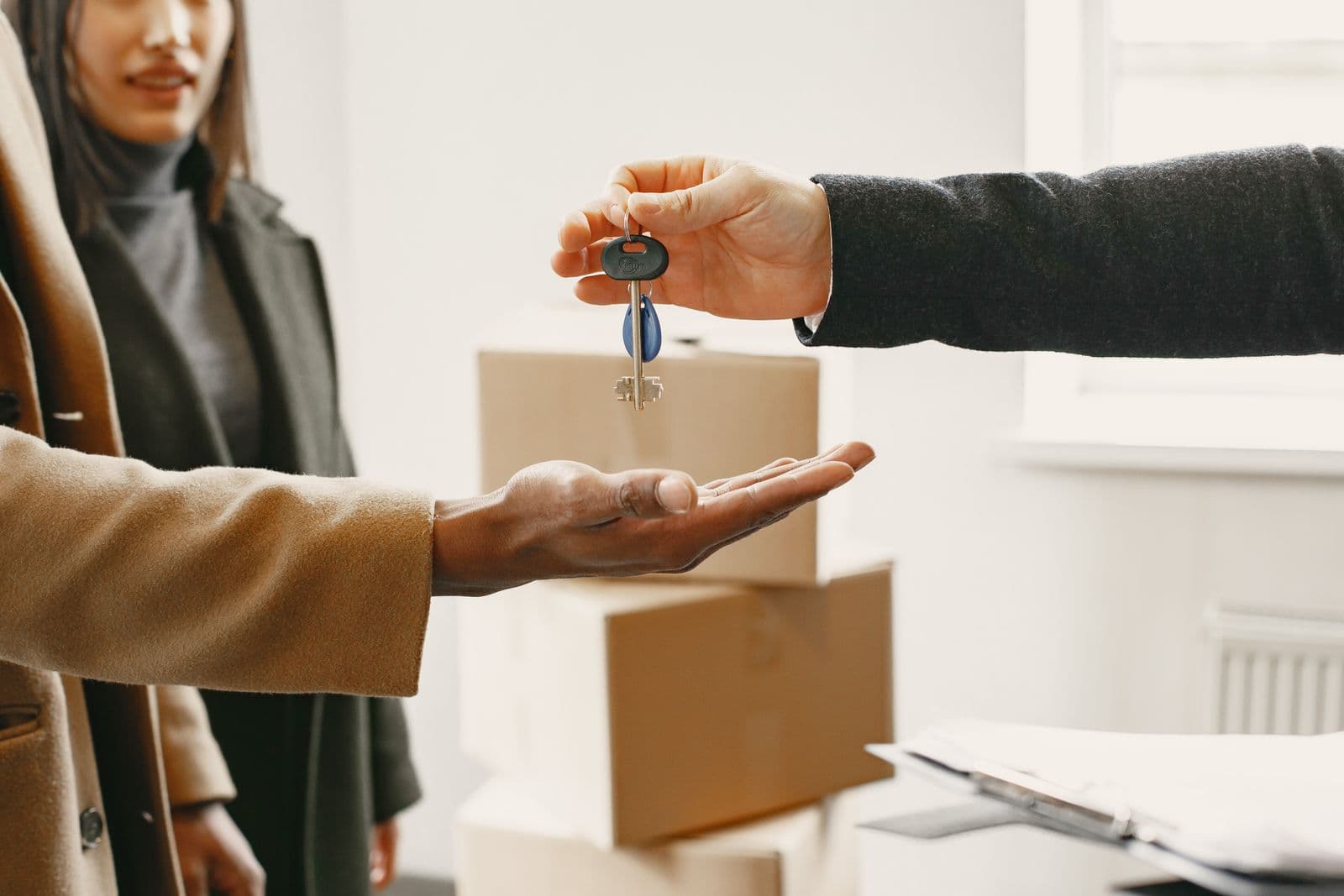 Keys being handed over in a flat surrounded by moving boxes